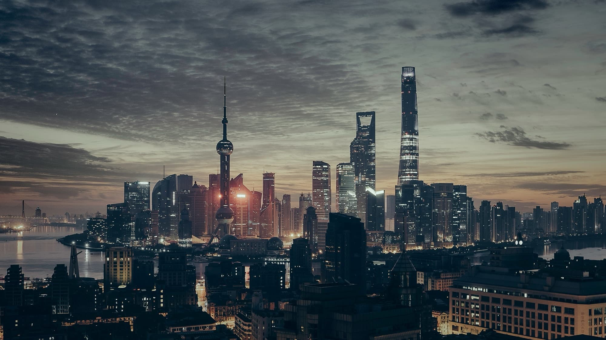 The Shanghai skyline at dusk, Oriental Pearl Tower and Shanghai Tower lit against the river